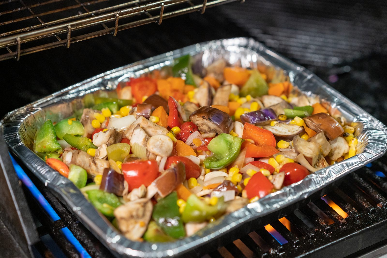 Vegetables and BBQ items finishing on the live grill during a Sunday Roast omakase service