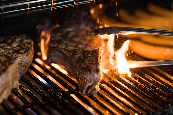 Steaks grilling over open flame during a Sunday Roast BBQ event in Singapore